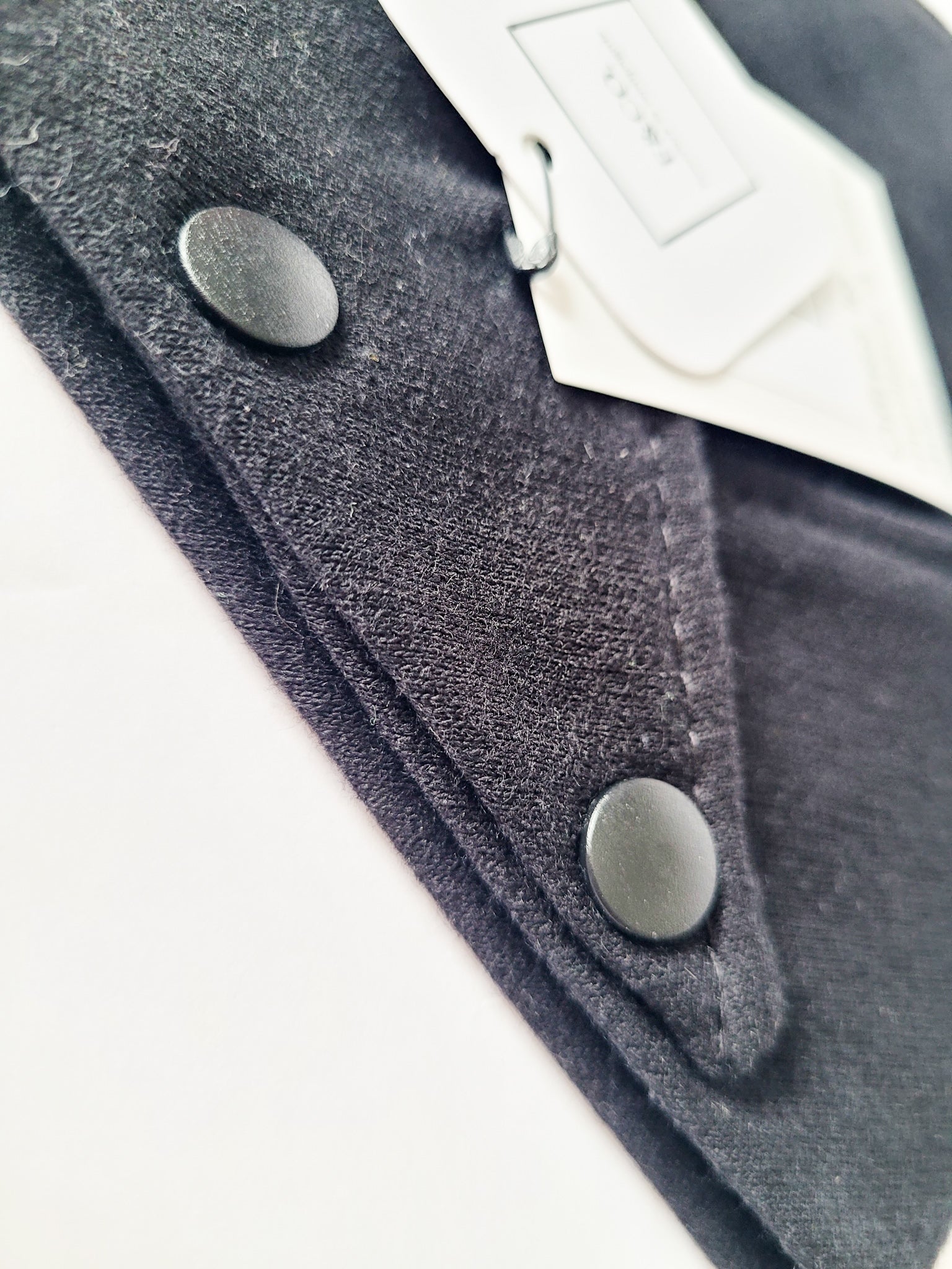 Gros plan sur les bouttons pression en plastique de couleur noir mat sur un tissus de coton ouaté noir.