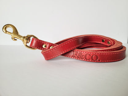 Laisse en cuir rouge pour chien. Attache en laiton. Logo estampé. Coutures rouges.