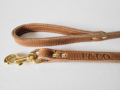 Laisse en cuir de couleur beige tan pour chien. Attache en laiton. Logo estampé.