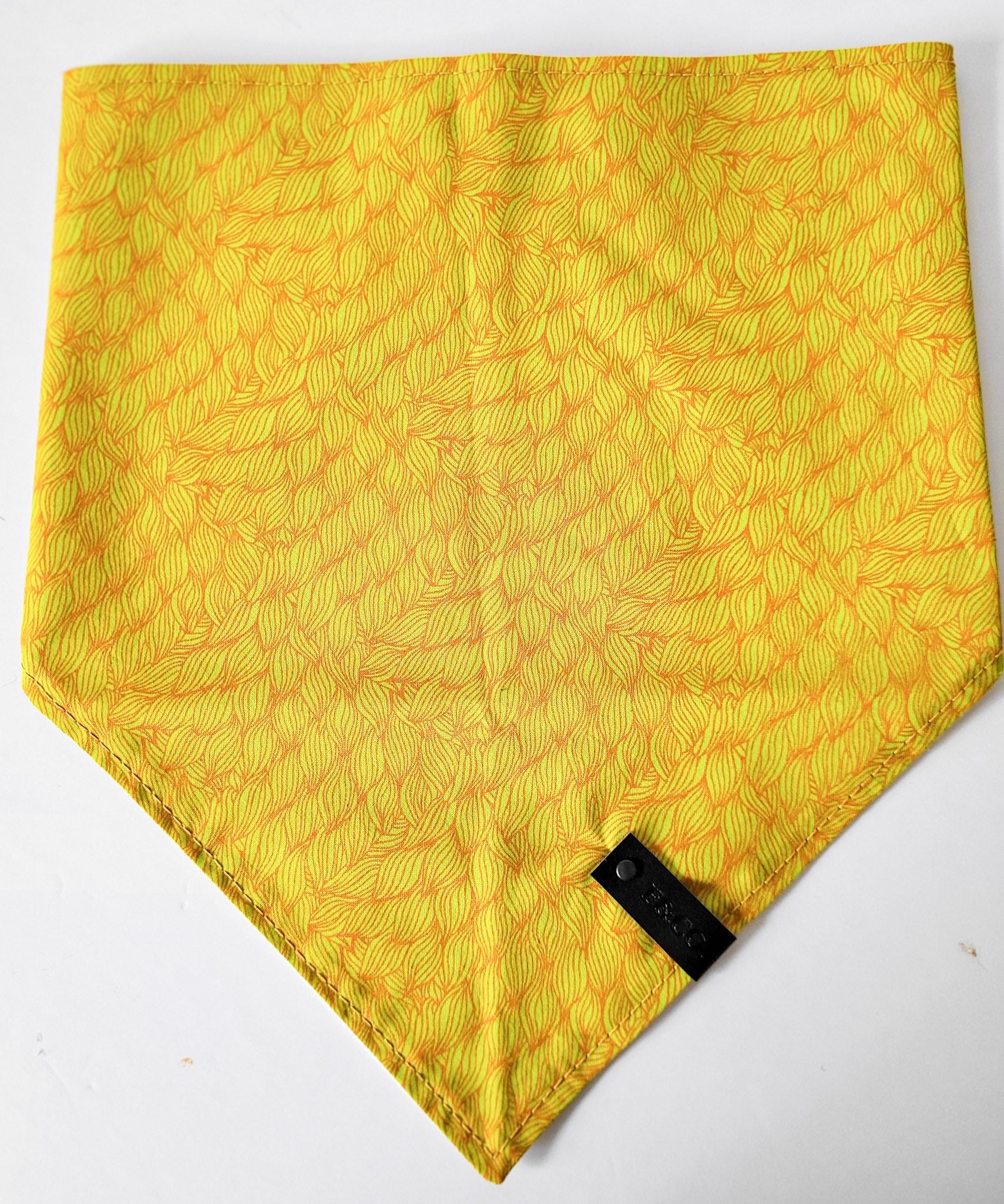 Bandanas déplié en coton tissé jaune orangé aux motifs abstraits. garni de notre étiquette de cuir végan noir