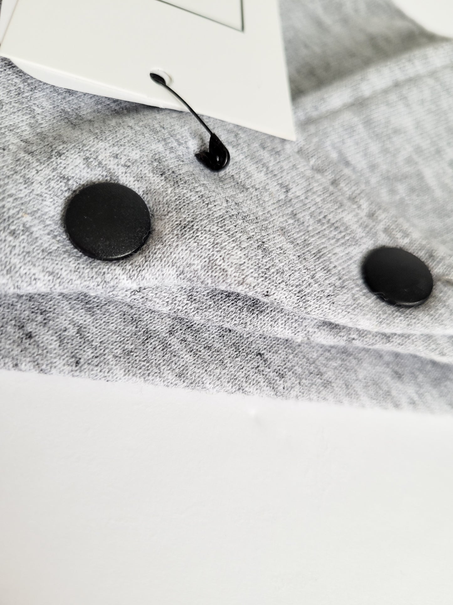 Gros plan sur bouton pression noir mat en plastique sur bandanas en coton ouaté gris chiné.