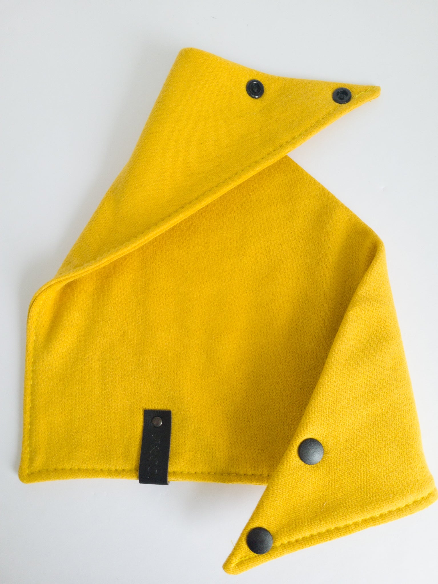Bandanas en coton ouaté jaune moutarde ouvert. Bouton pression noir mat en plastique et étiquette de cuir végan noir.