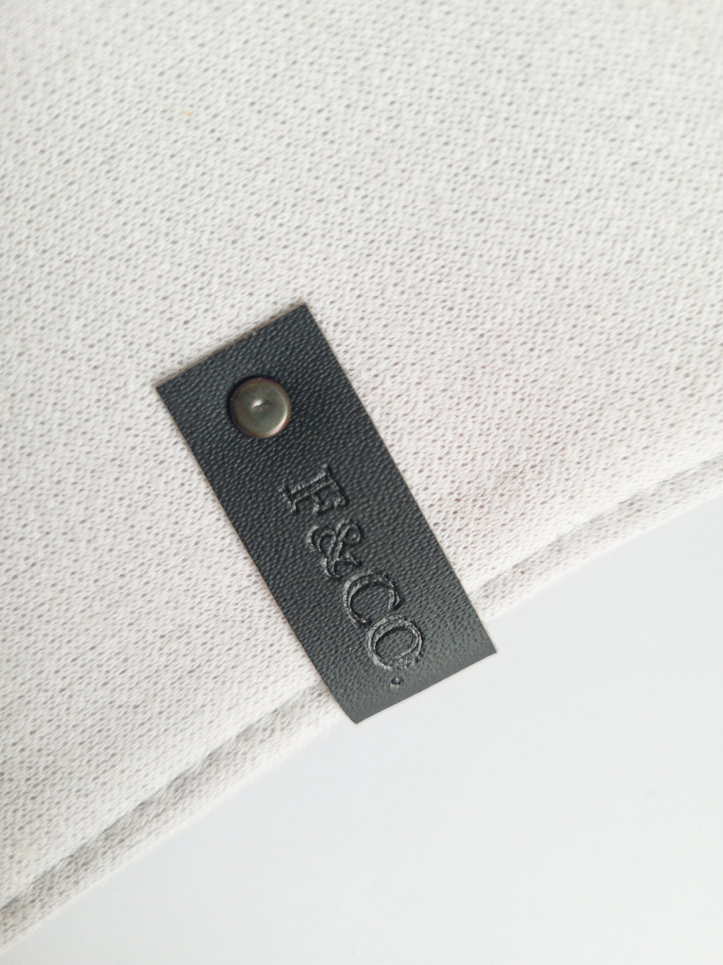 Gros plan sur l'étiquette de cir végan noir sur le bandanas de coton ouaté gris clair.
