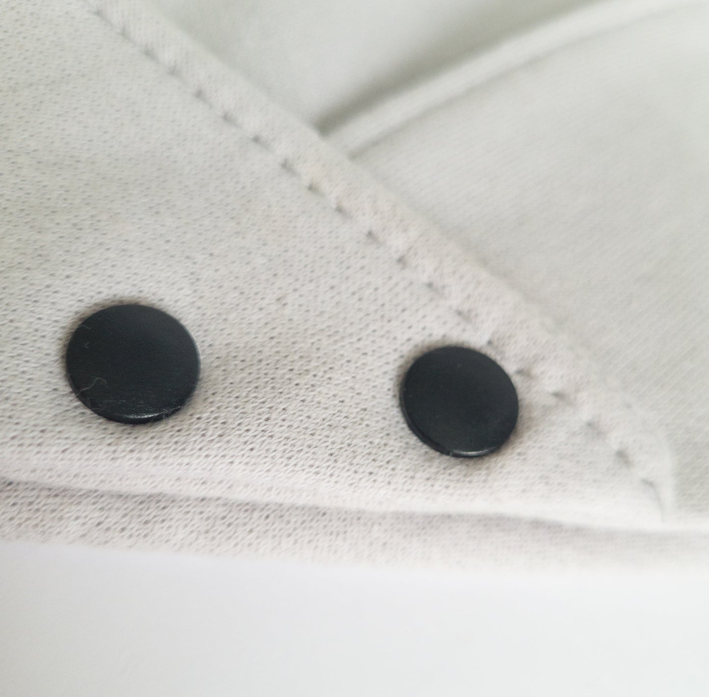 Gros plan sur les boutons pressions noir en plastique de notre bandanas de coton ouaté gris clair.