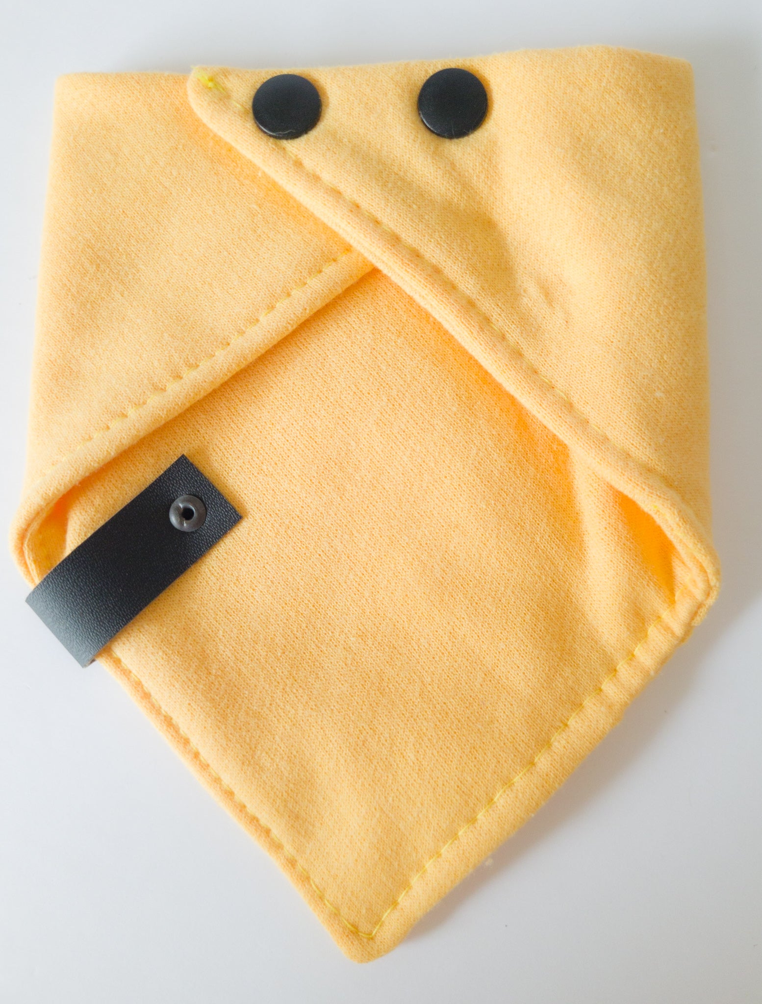 Verso du bandanas de coton ouaté de couleur jaune blé avec étiquette de cuir végan noir et boutons pression noir mats en plastiques.